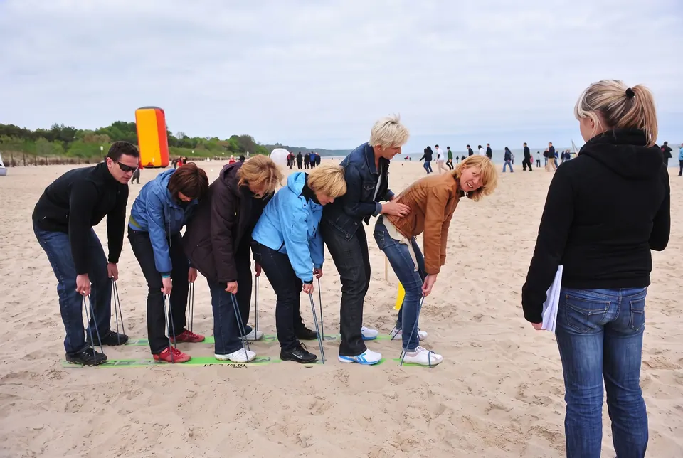 Drużyna na plaży przesuwa się na wspólnych deskach trzymanych na linkach