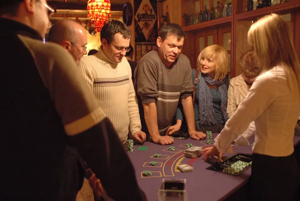 Uczestnicy grają przy stole do blackjacka w wieczorowej sali kasyna