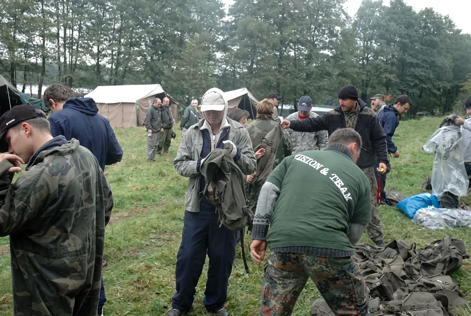 Uczestnicy przebierają się w mundury moro na polanie z namiotami