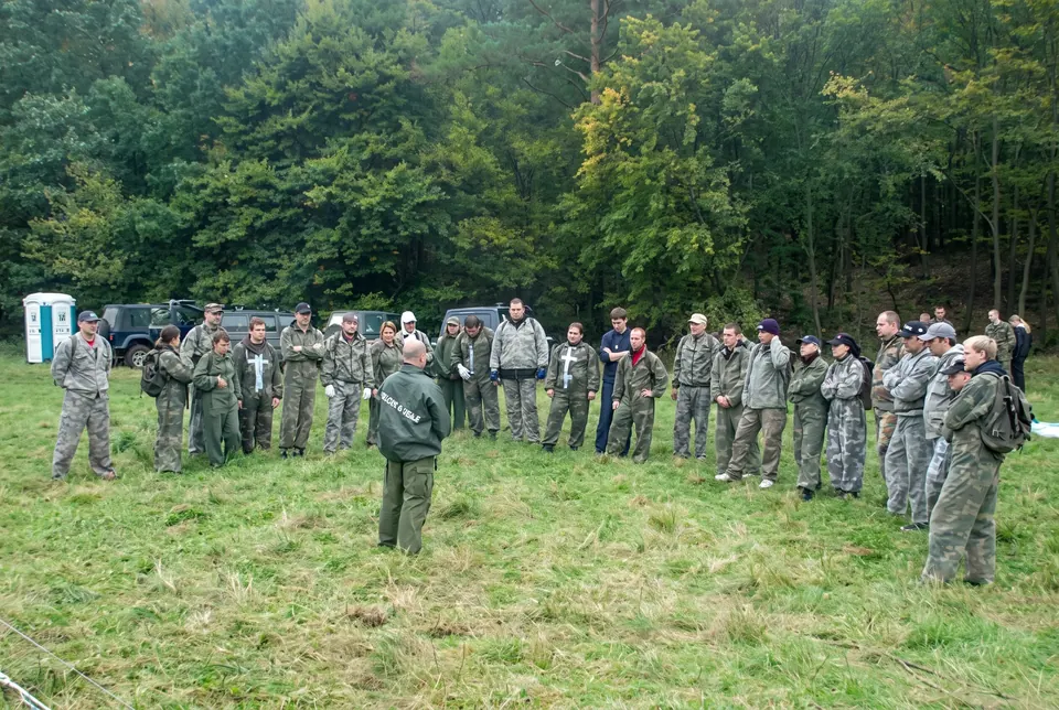 Grupa w mundurach moro słucha instruktora na leśnej polanie