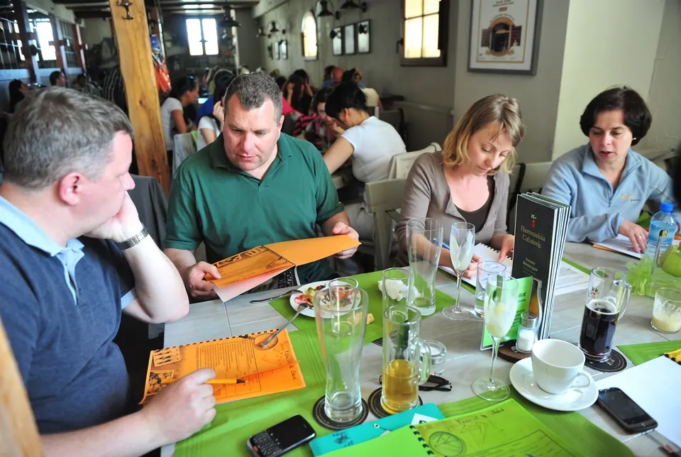 Uczestnicy przy stole w restauracji wypełniają pomarańczowe karty zadań